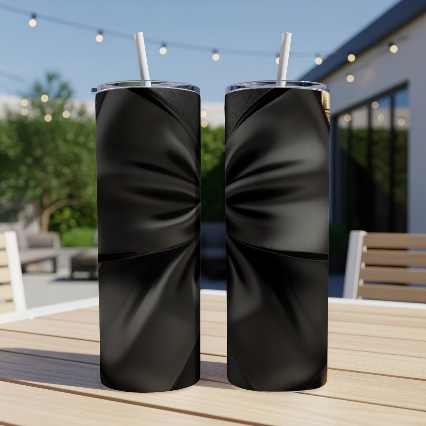 Two black tumblers with a textured ribbon design sit on a table outdoors.