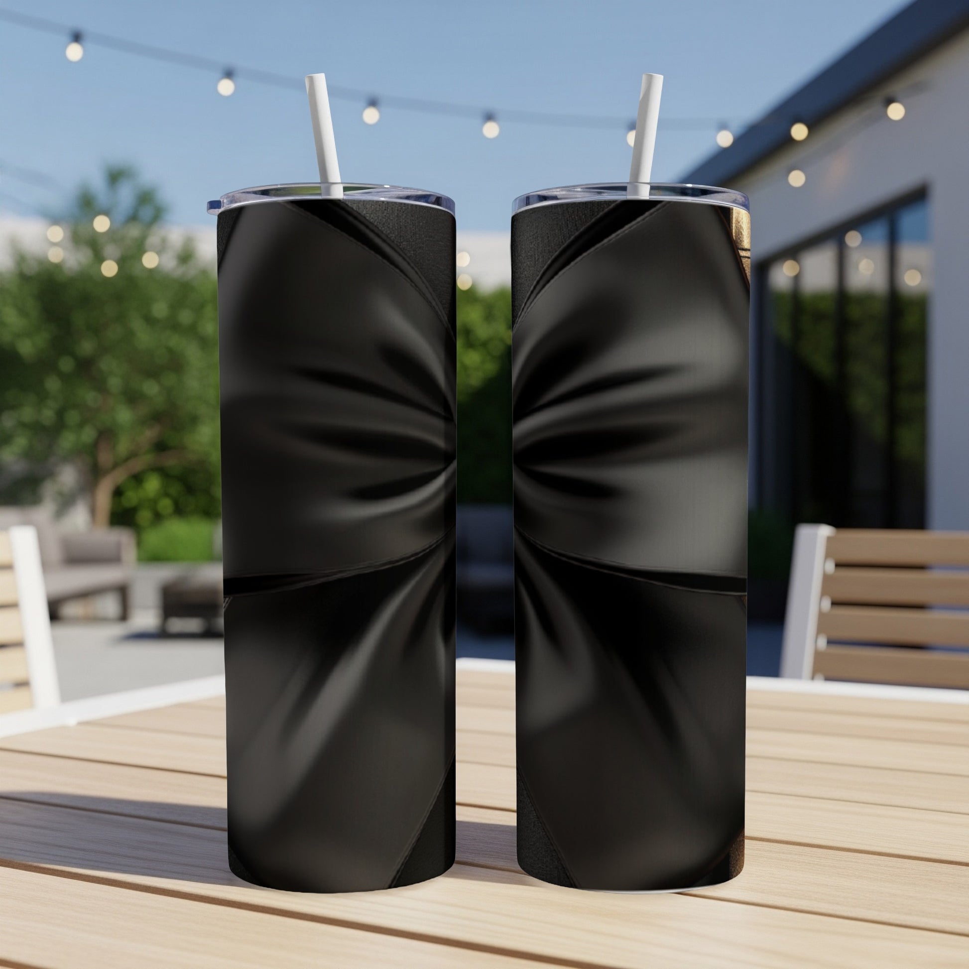 Two black tumblers with a textured ribbon design sit on a table outdoors.