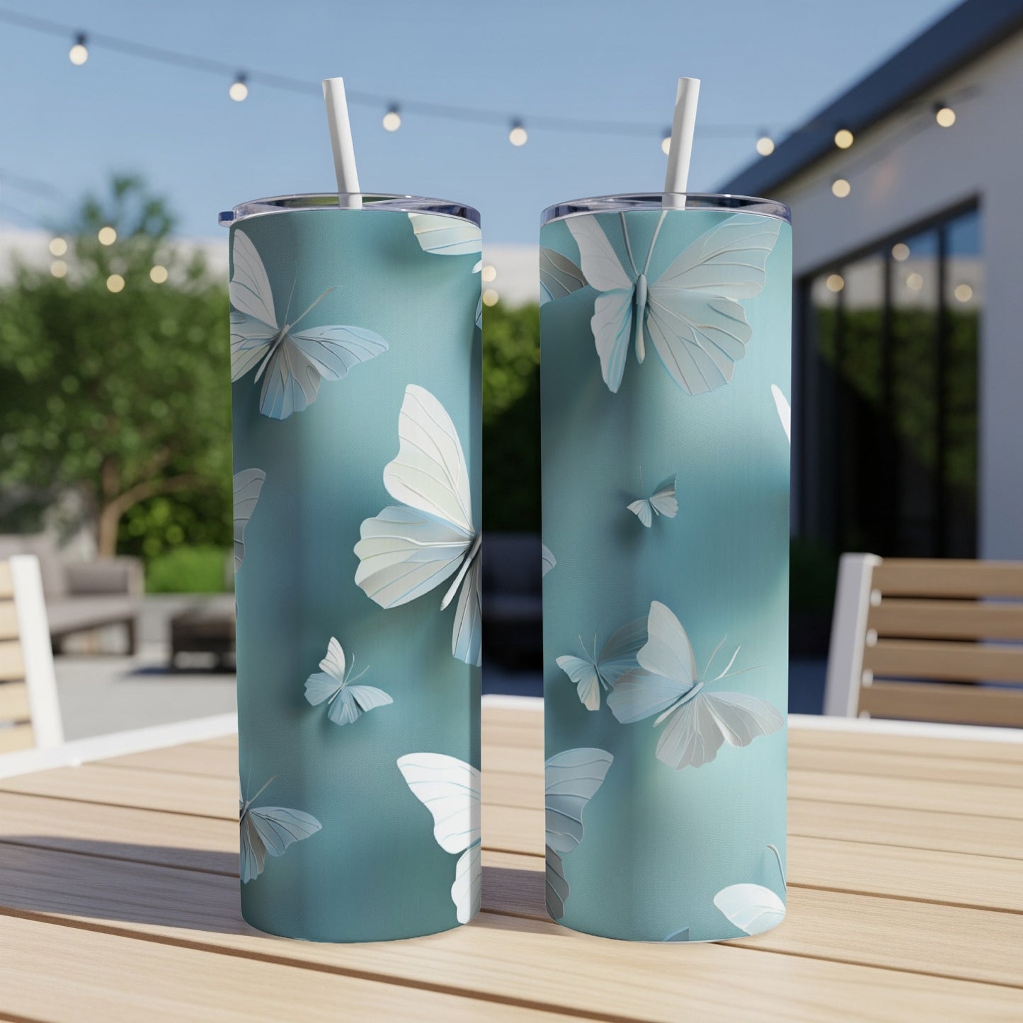 Two tall teal tumblers with a repeating pattern of white butterflies.