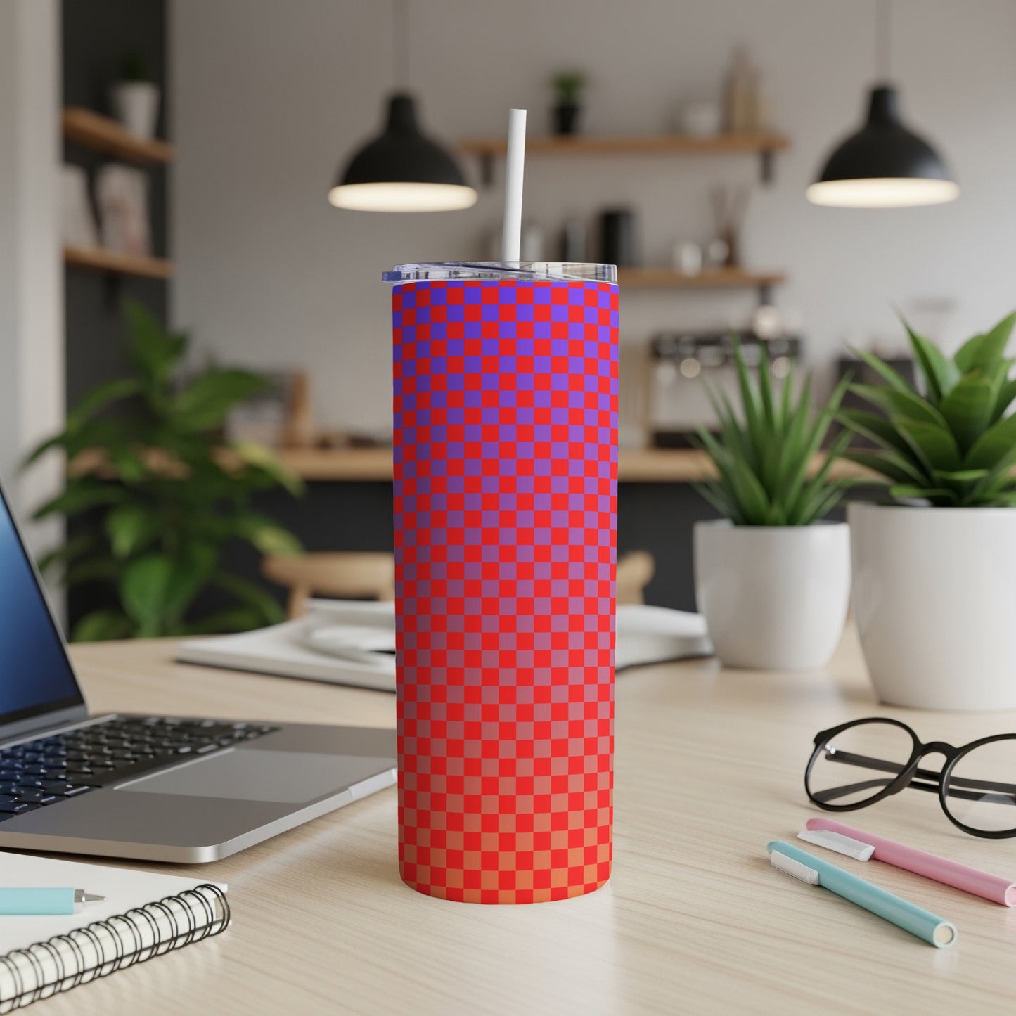 Red and blue checkered tumbler with white straw on desk with laptop.