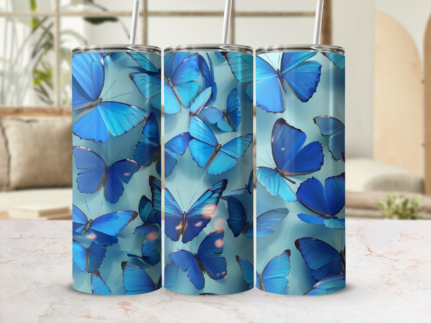 Three blue butterfly tumblers on a marble surface with blurred background.