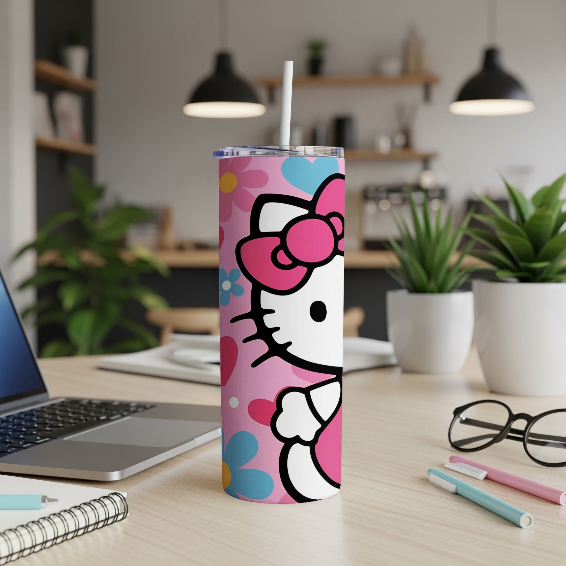 Pink Hello Kitty tumbler with flowers and straw on a desk.
