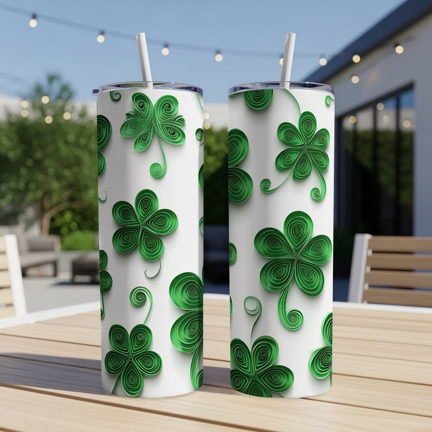 Two white tumblers with green quilled shamrock designs sit on a table.