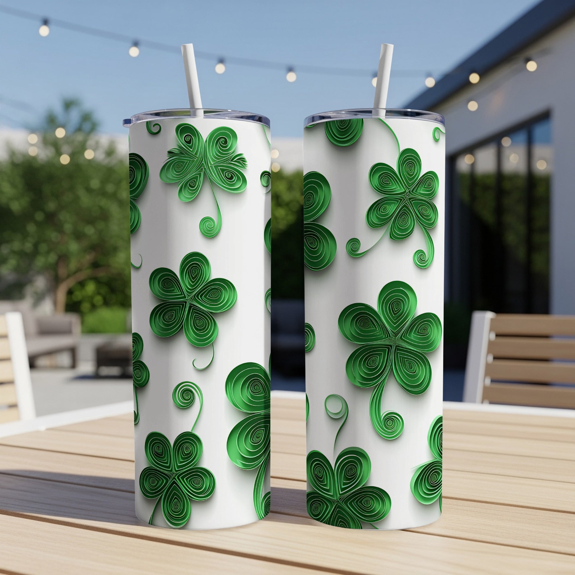 Two white tumblers with green quilled shamrock designs sit on a table.