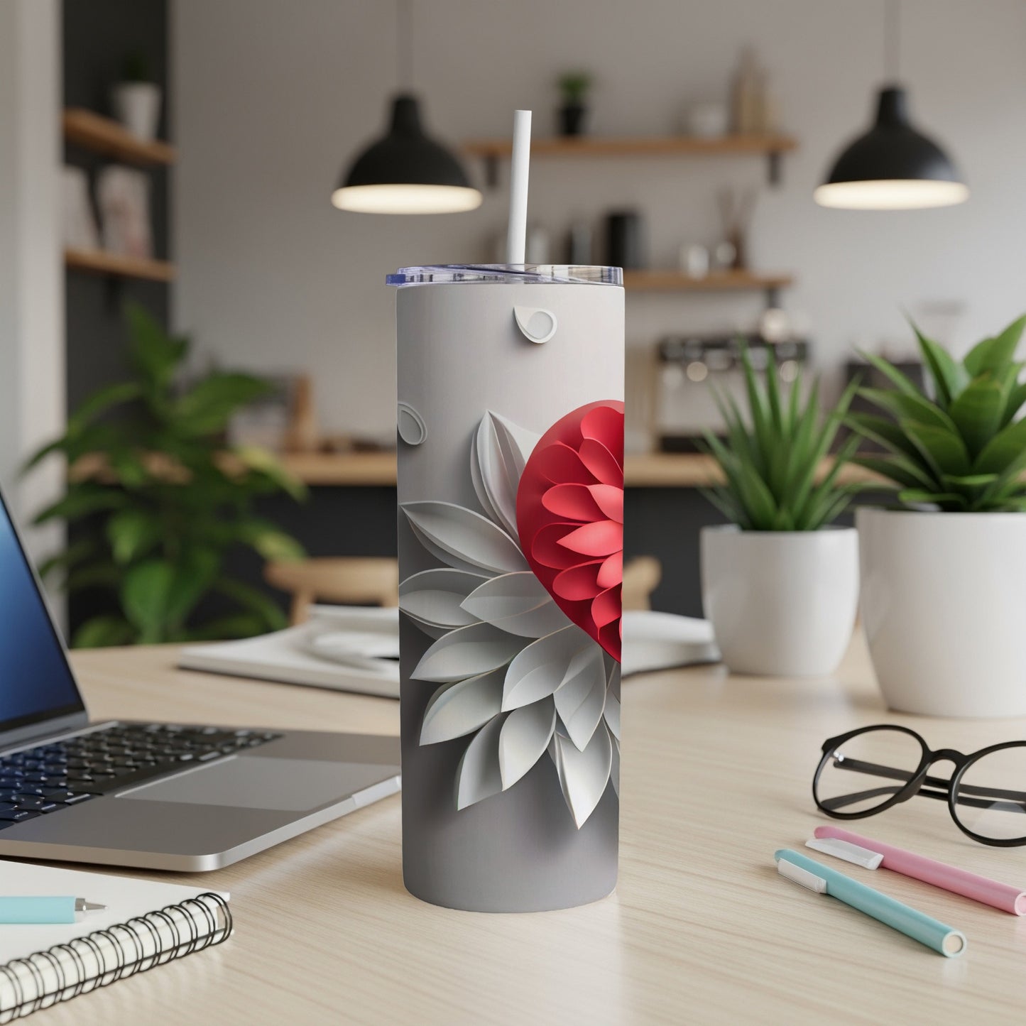 Gray tumbler with a red floral design and white petals.