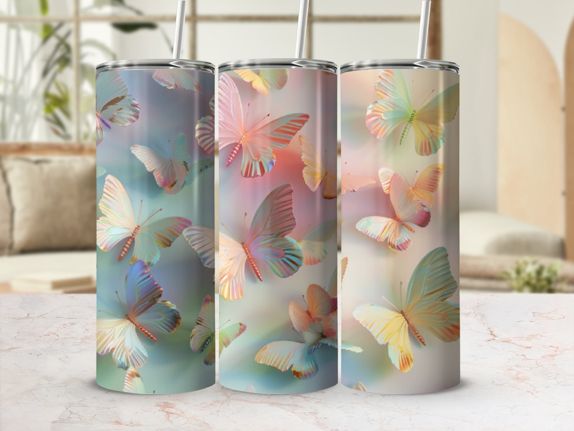 Three tumblers with colorful butterfly designs, displayed on a marble surface.