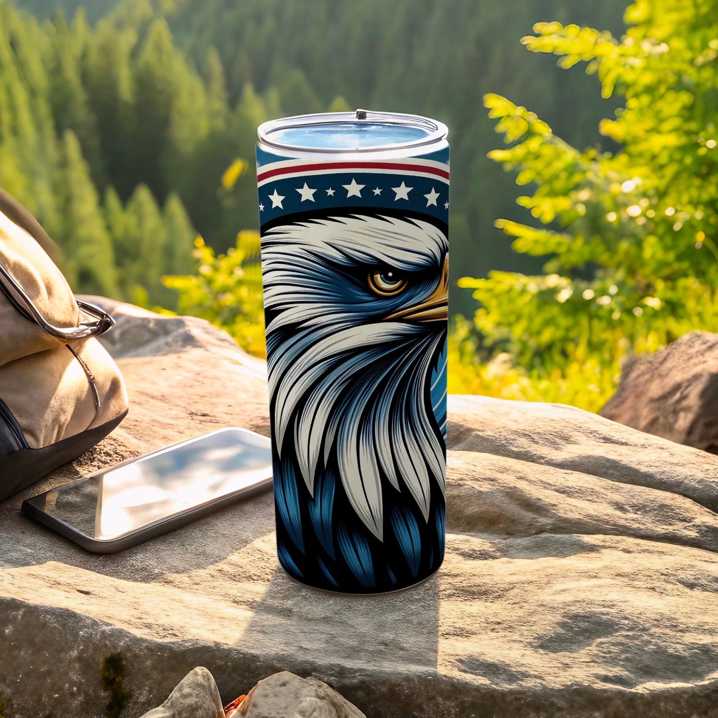 Patriotic eagle tumbler with striped lid on rocky outdoor surface.