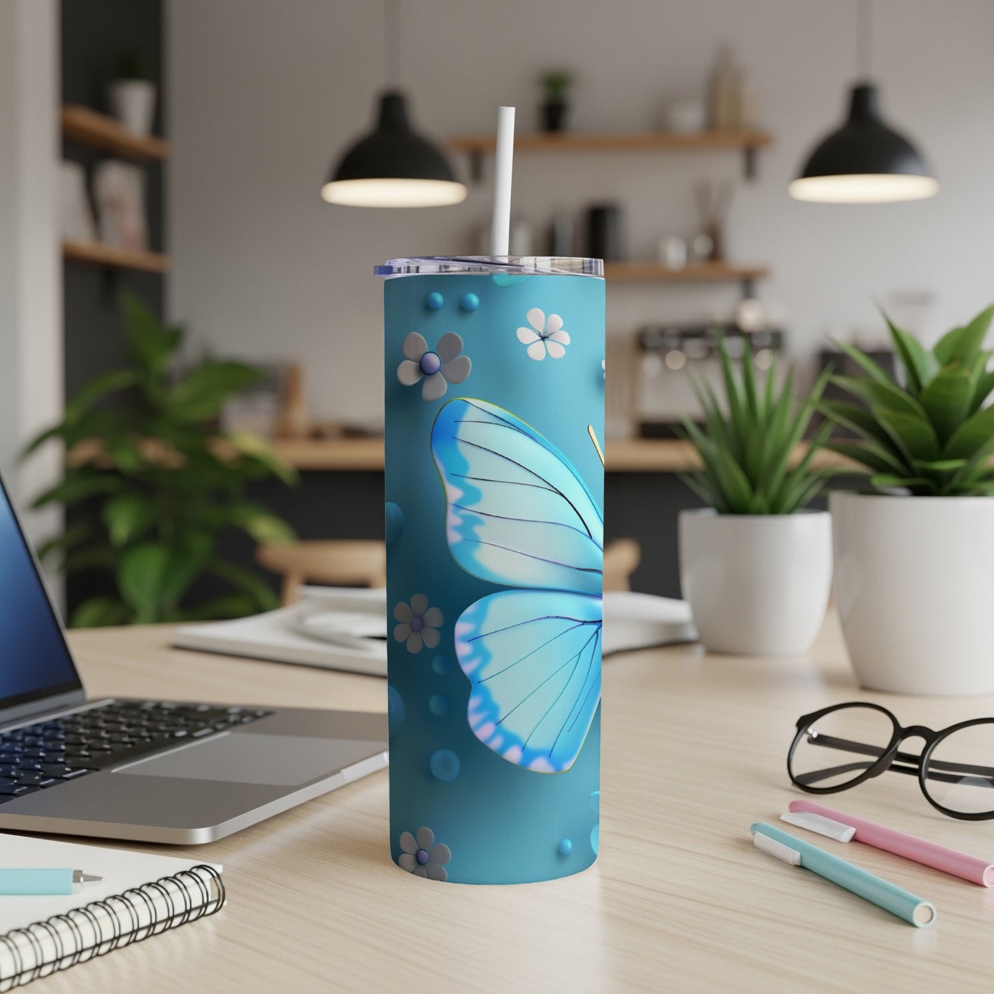 Blue butterfly tumbler with floral accents on a desk.