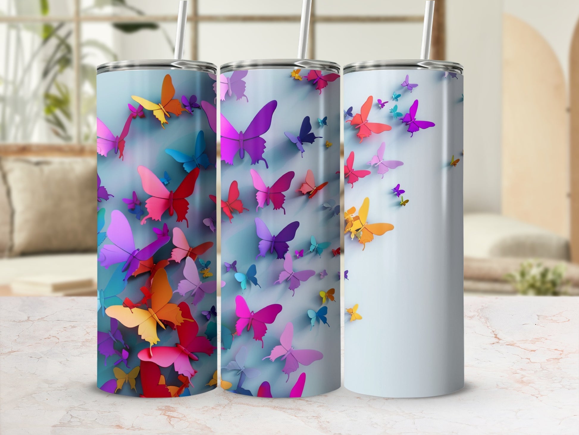 Three tumblers with colorful butterfly designs on a light surface.
