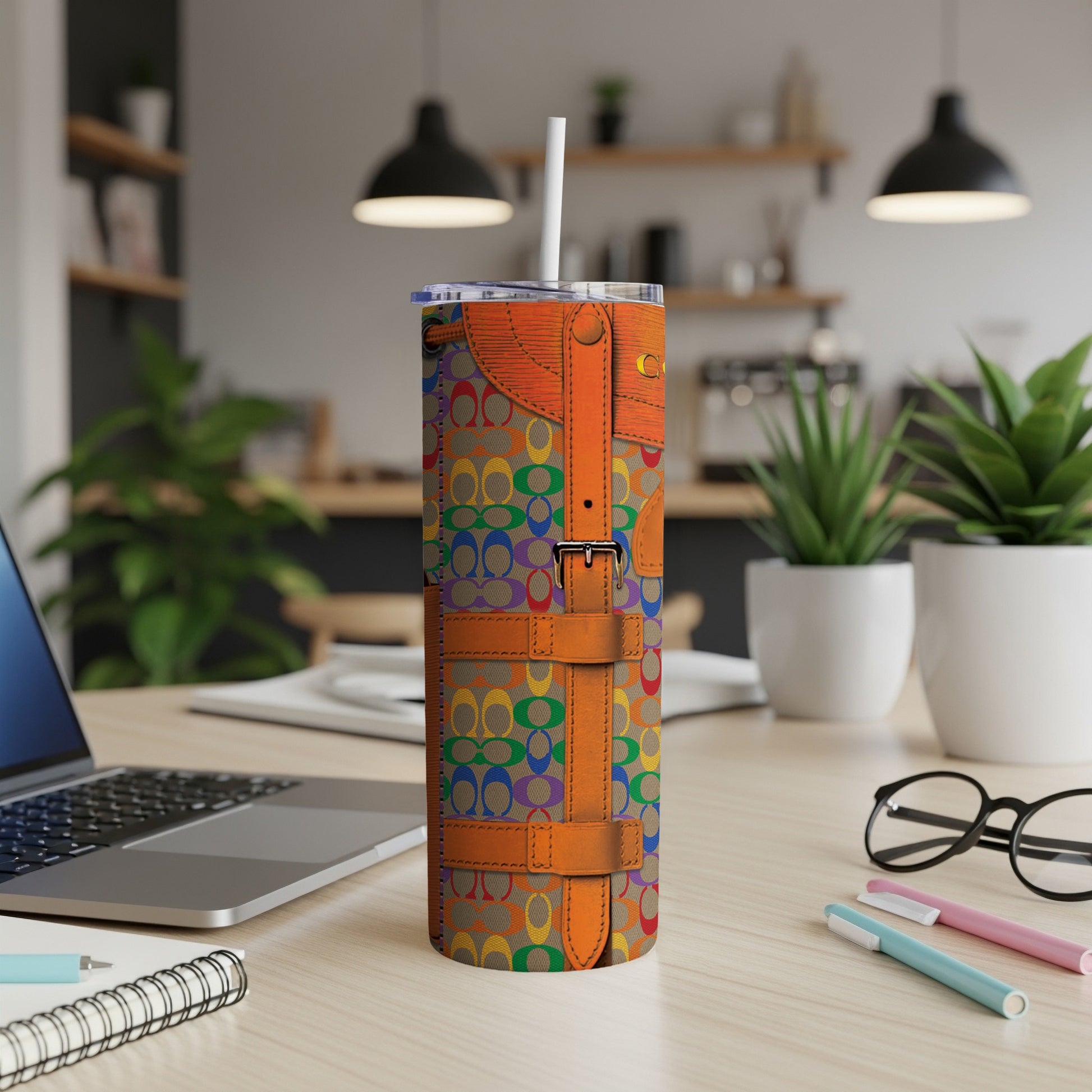 Tumbler with rainbow Coach logo pattern and orange strap details.