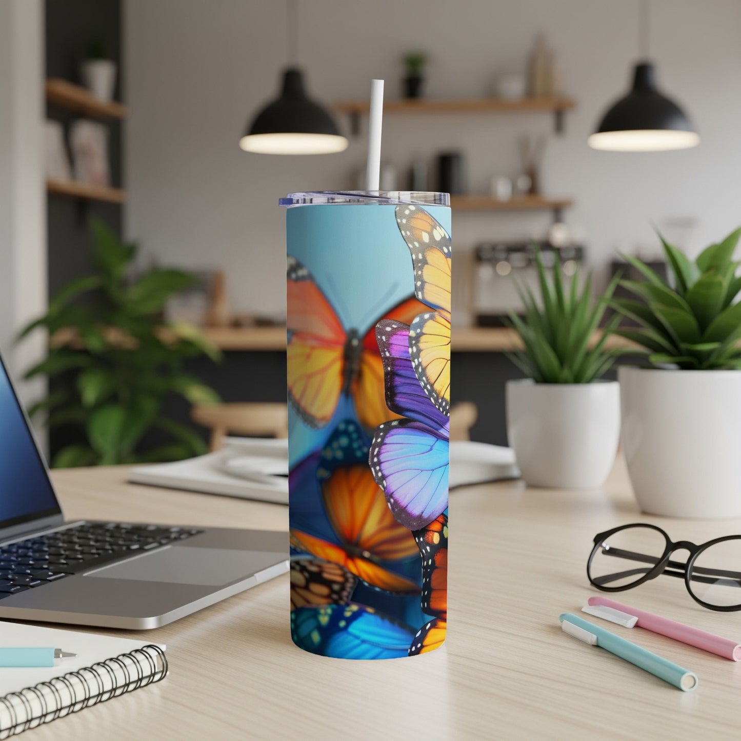 Colorful butterflies adorn a tall, insulated tumbler on a desk.