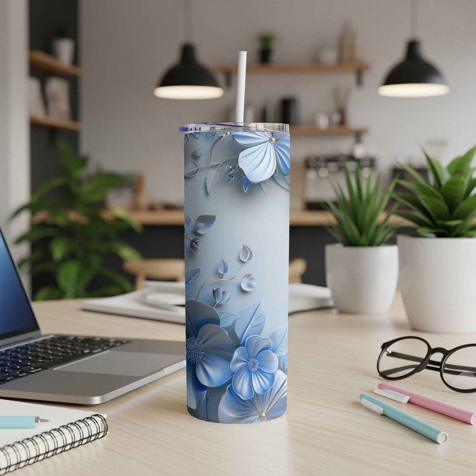 Blue floral patterned tumbler with a straw on a desk.