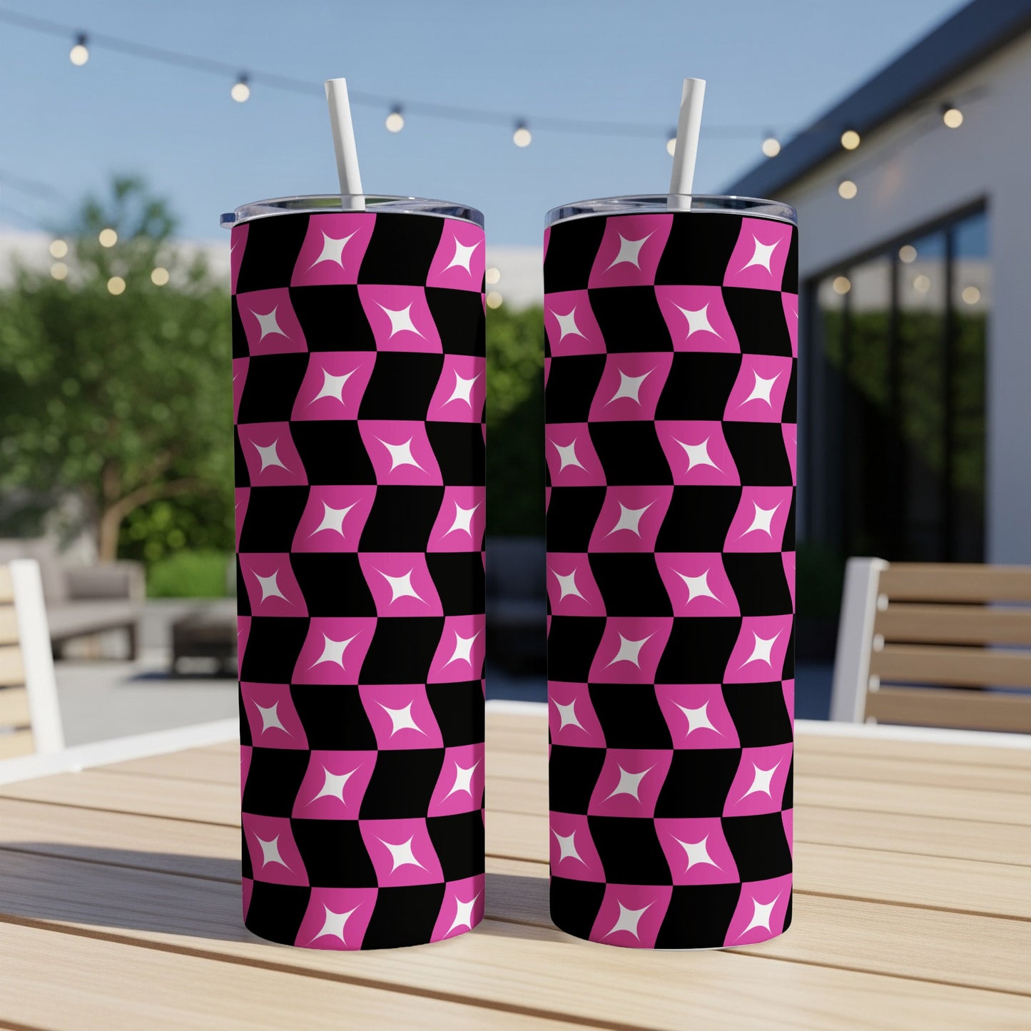 Two tall tumblers with a pink and black checkerboard pattern sit on a wooden table.