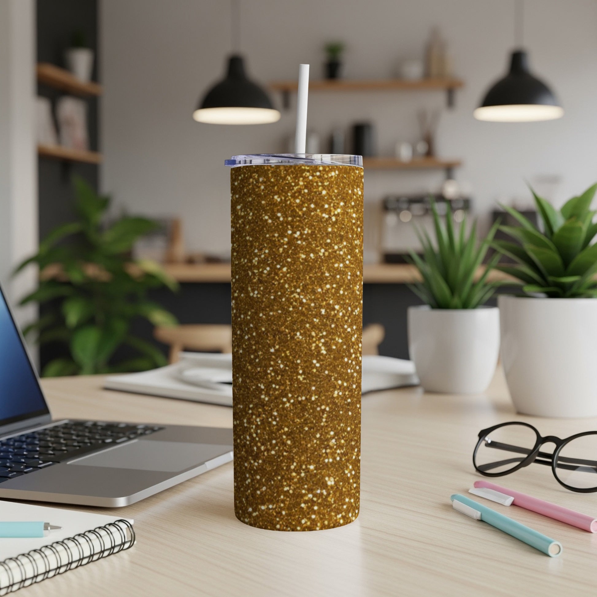 Gold glitter tumbler with white straw on a desk with laptop.