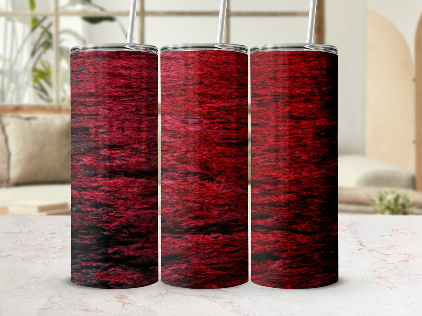 Three tumblers with a deep red wavy water pattern stand on a marble surface.
