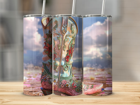 Floral patterned cowboy boot tumbler with straw against a cloudy sky backdrop.