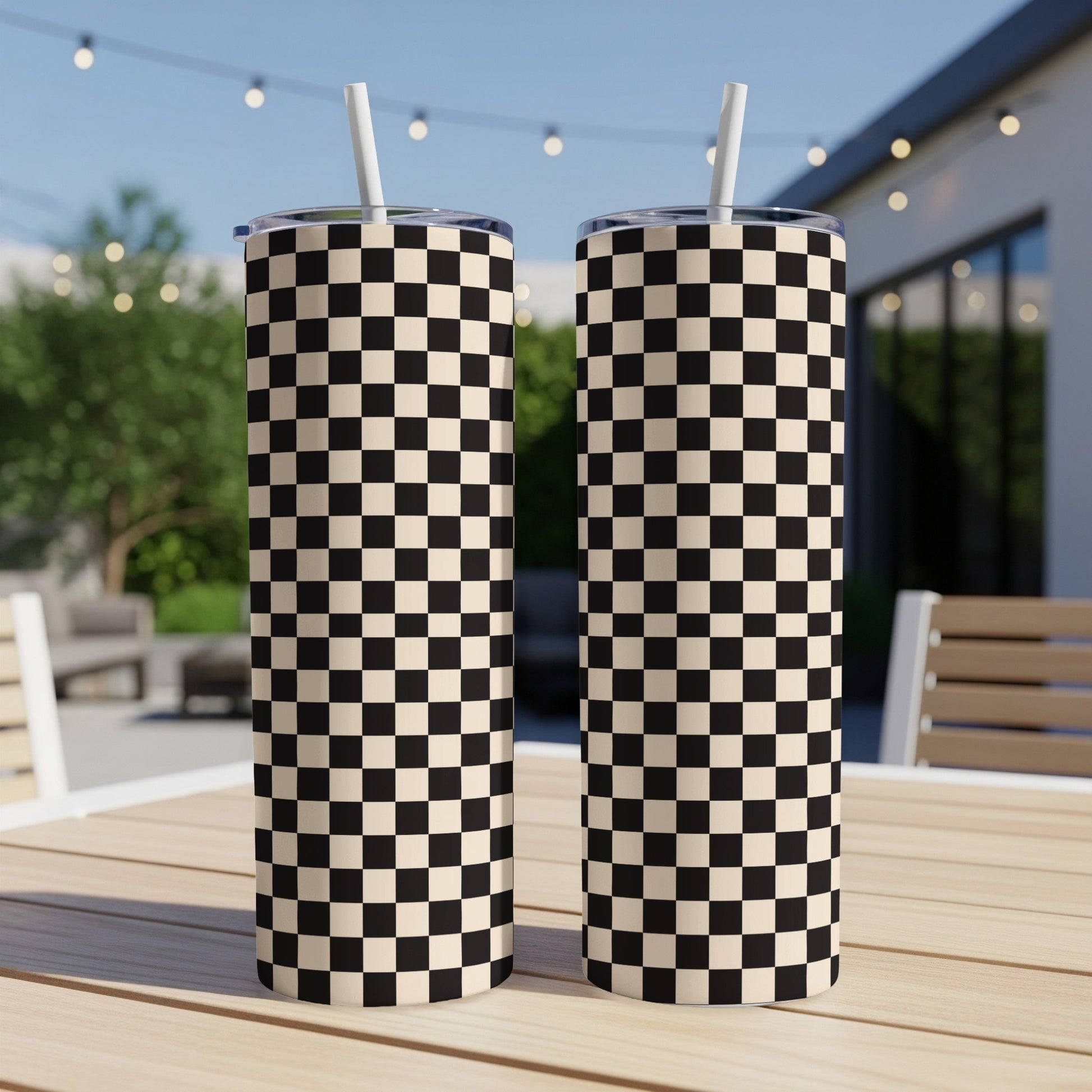Two tall tumblers with a black and white checkerboard pattern and white straws.