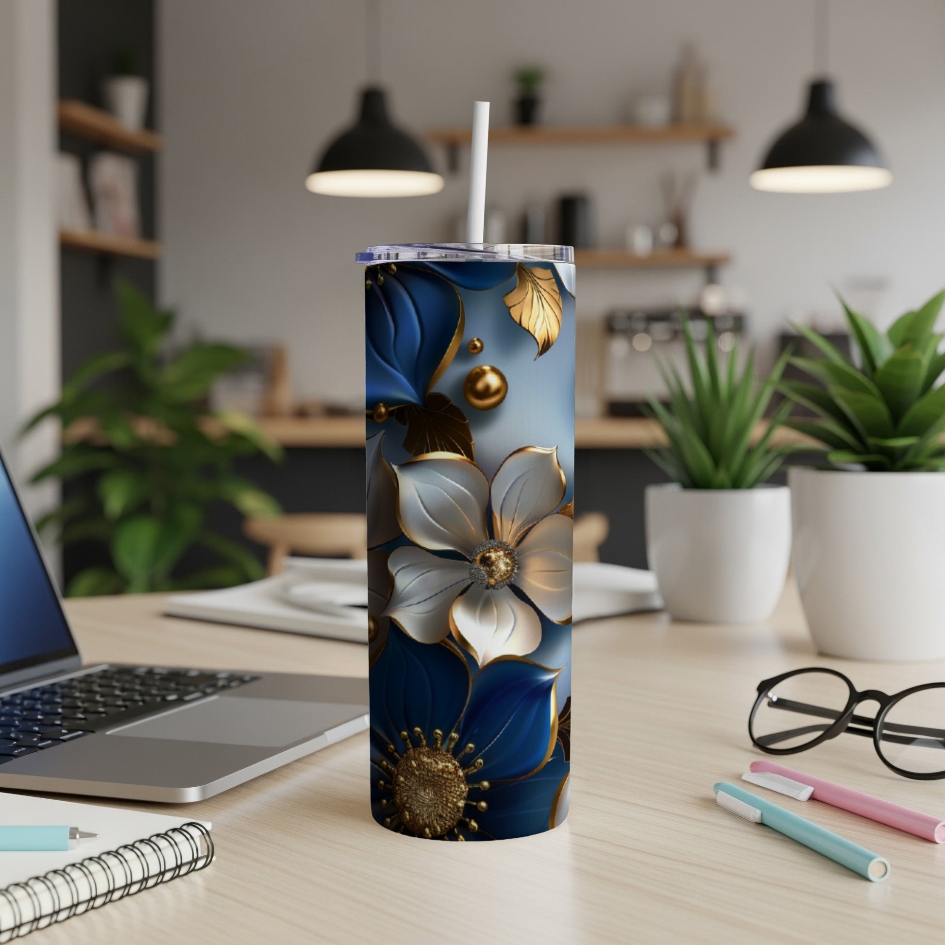 Blue and gold floral tumbler with white straw on a desk.