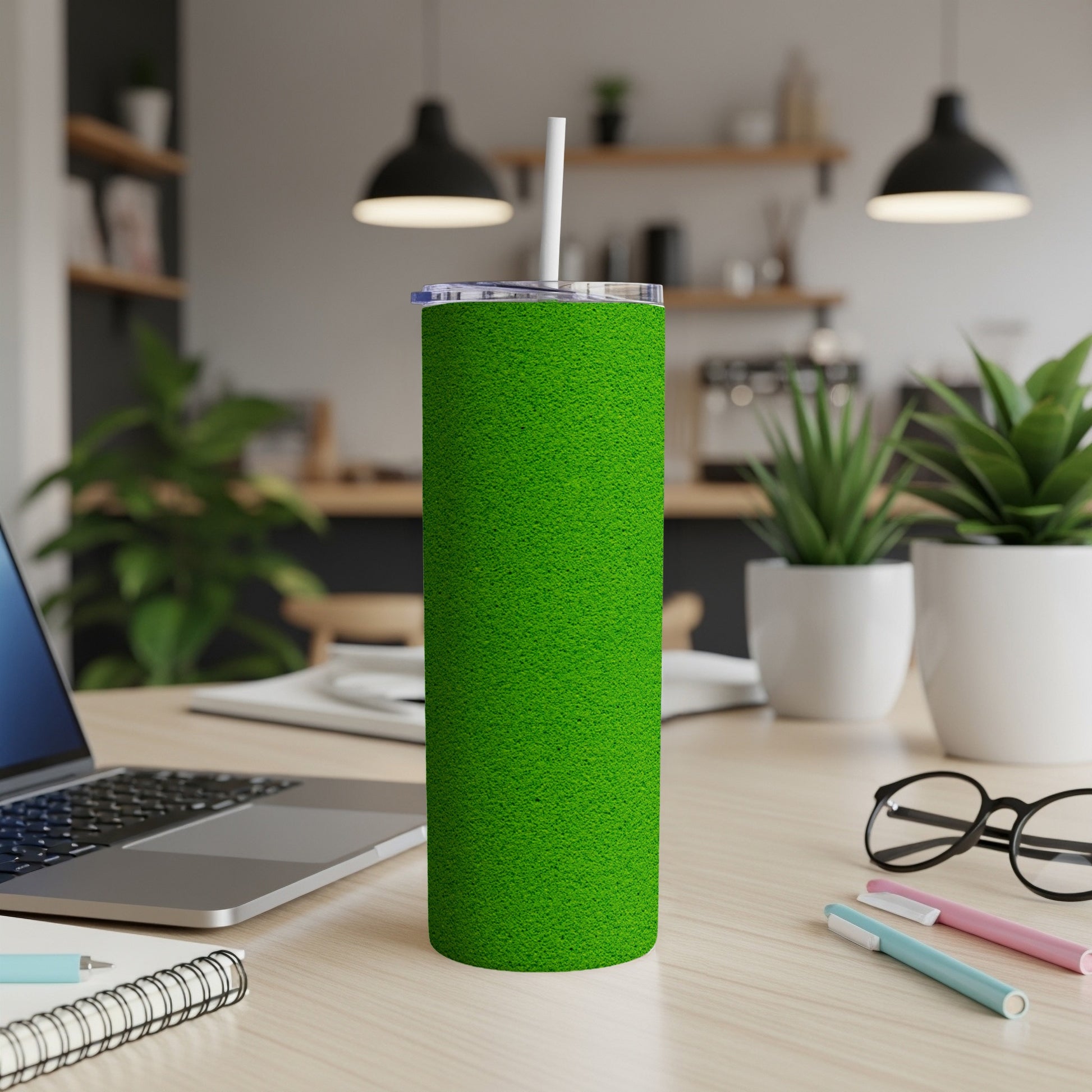 Green textured tumbler with white straw on a desk.
