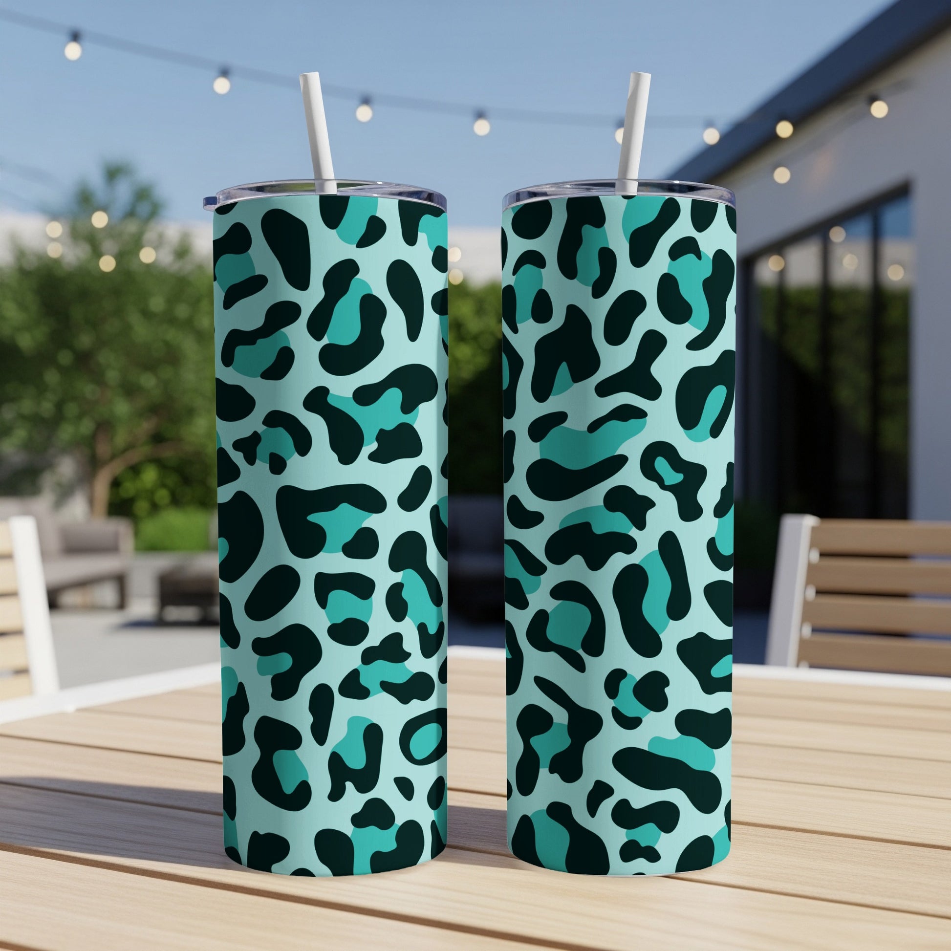 Two tall tumblers with teal and black leopard print and white straws.