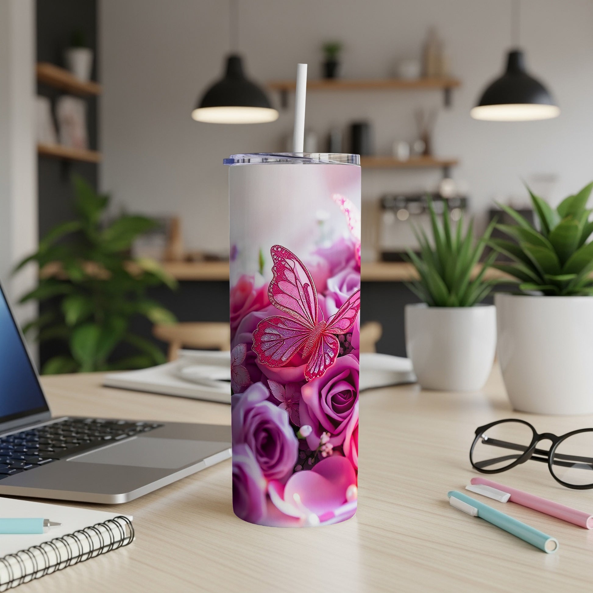 Tumbler with a pink butterfly and roses design, set on a desk.