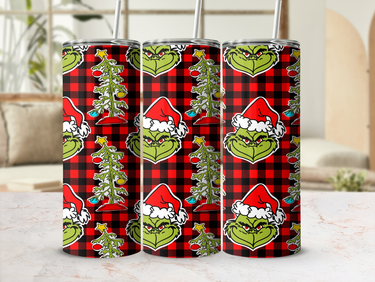 Three Grinch tumblers with Santa hats and Christmas trees on red plaid background.