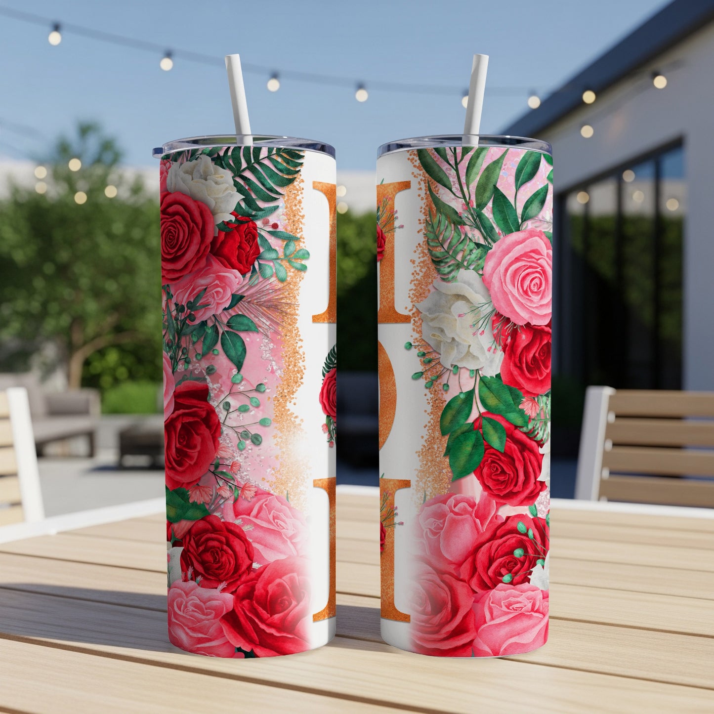 Two white tumblers with floral design and gold accents on a wooden table.