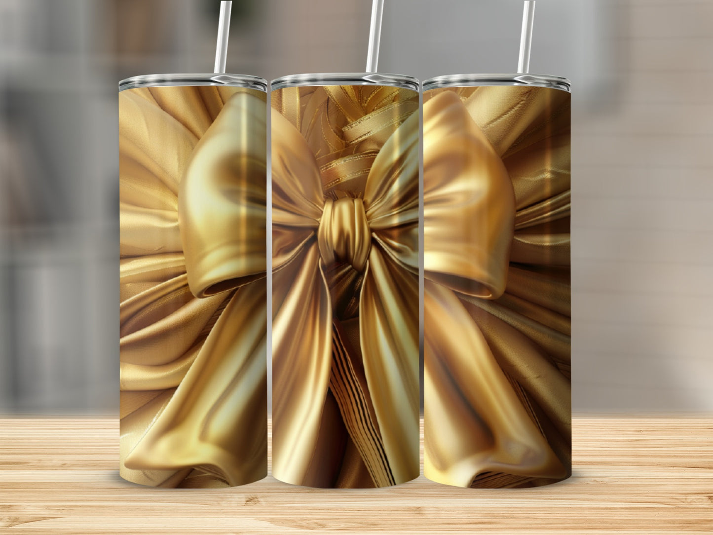 Three tall, golden gift ribbon tumblers with straws on a wooden surface.