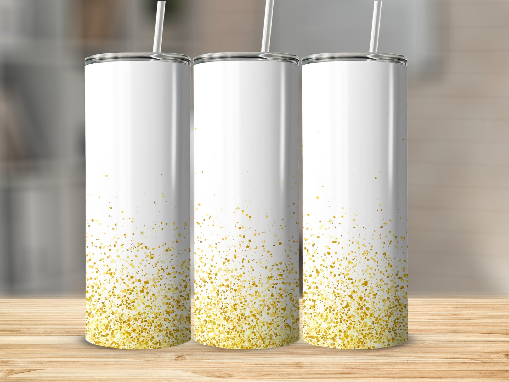 Three white tumblers with gold glitter design, standing on a wooden surface.