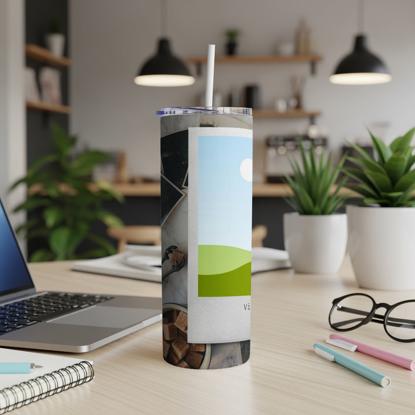 Tumbler with landscape photo and sugar cubes, on a desk with laptop and plants.