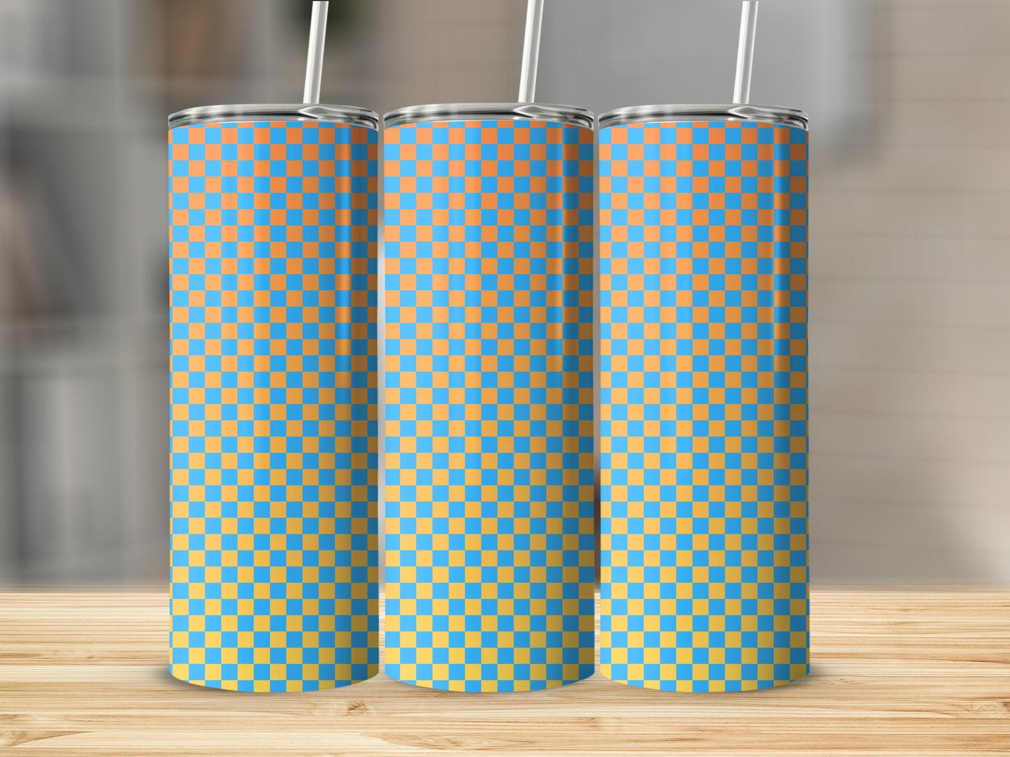 Three blue and orange checkered tumblers with straws on a wooden surface.