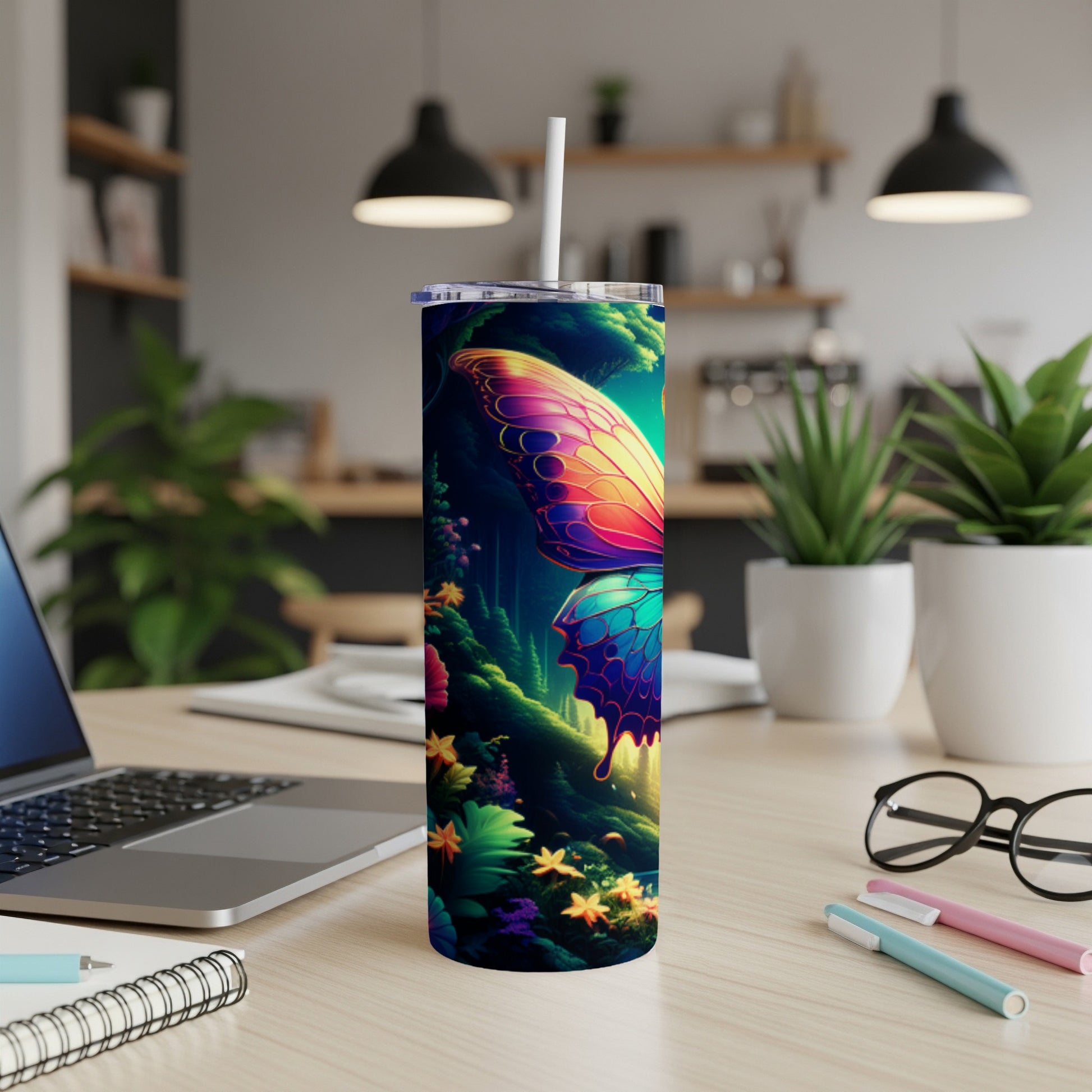 Butterfly tumbler with vibrant wings on a desk with laptop and pens.