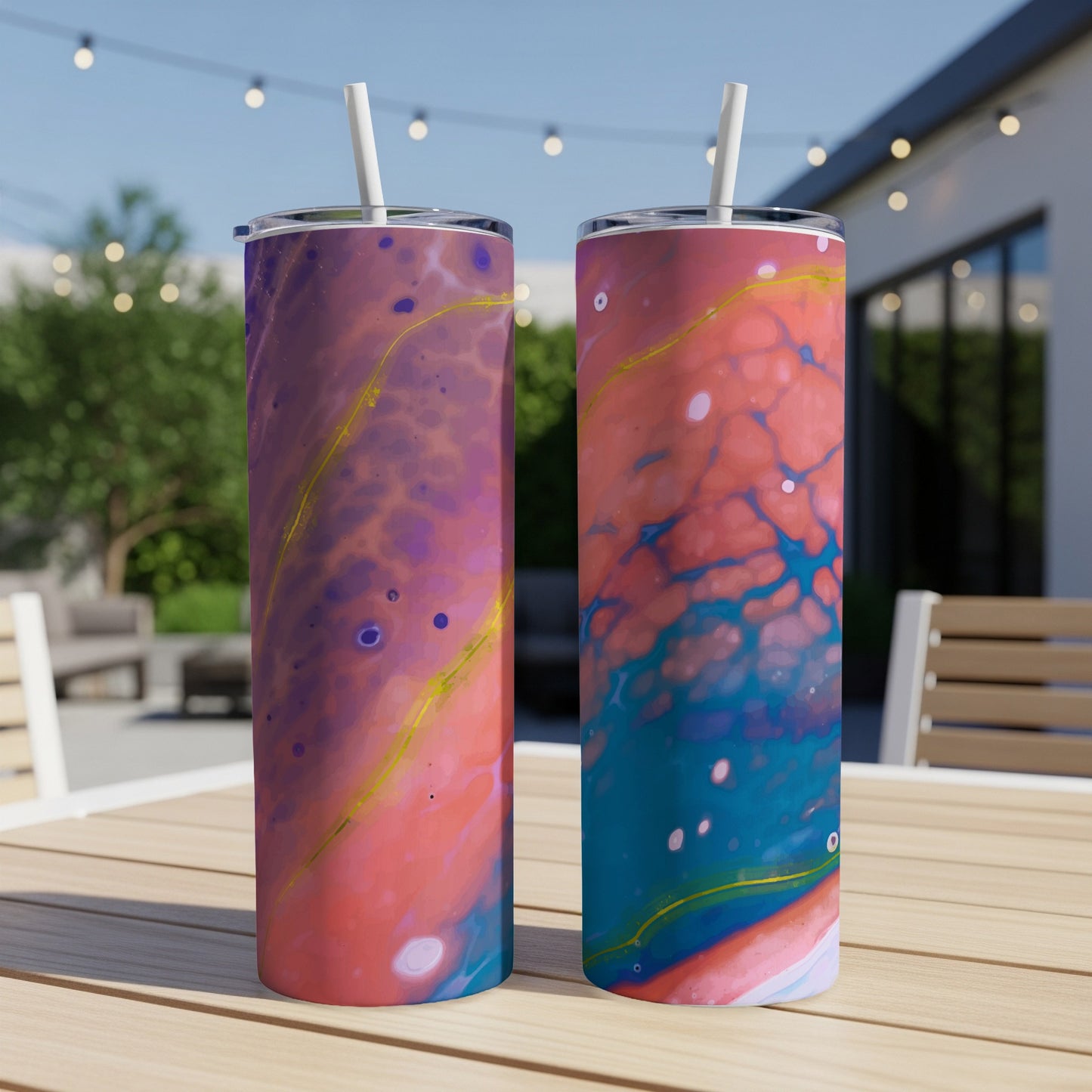 Two tumblers with abstract fluid art patterns in pink, purple, blue, and yellow on a wooden table outdoors.
