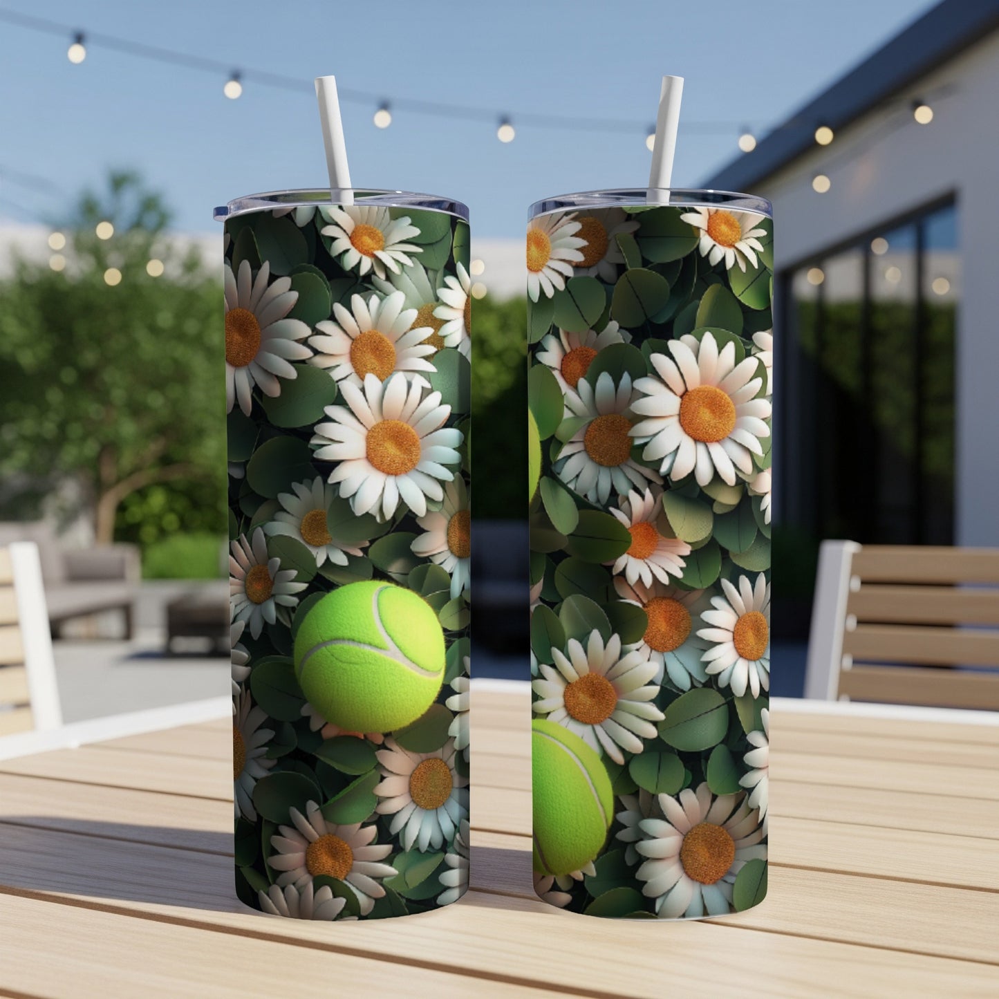 Two tumblers with a white daisy and tennis ball design on an outdoor table.