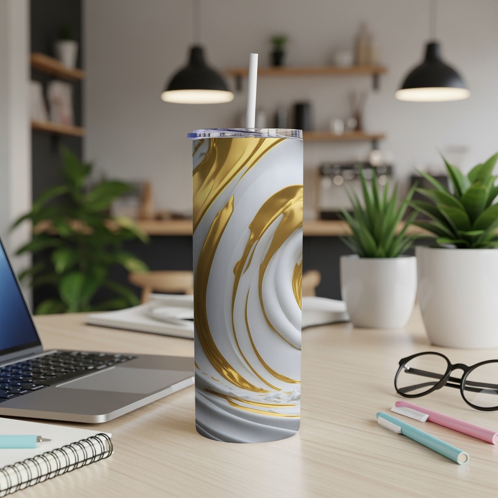 White and gold abstract swirl tumbler with straw on desk.