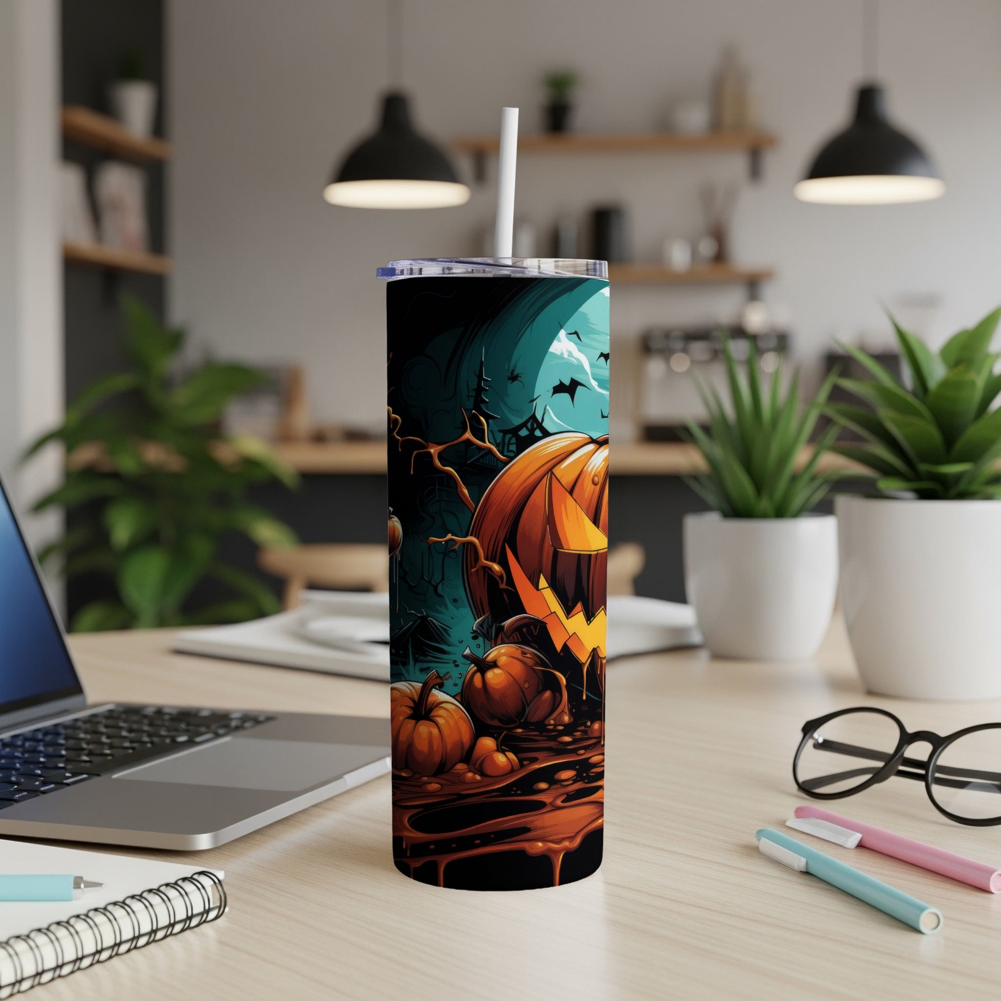 Halloween tumbler with jack-o'-lantern, pumpkins, bats, and moon on a desk.