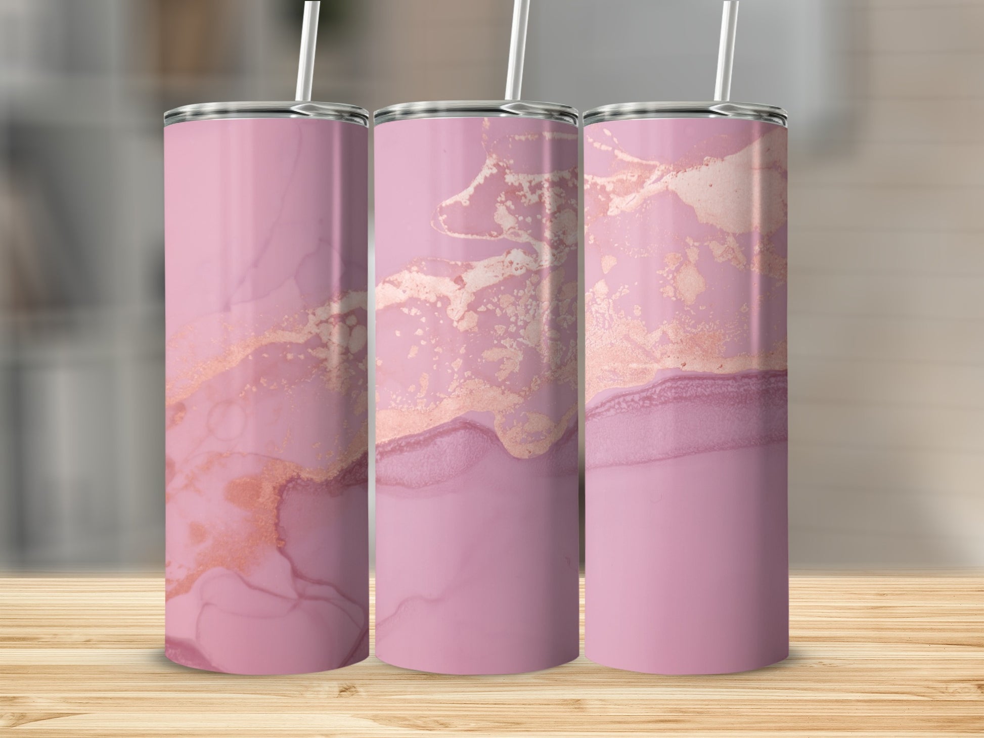 Three pink tumblers with rose gold marble pattern on wooden surface.