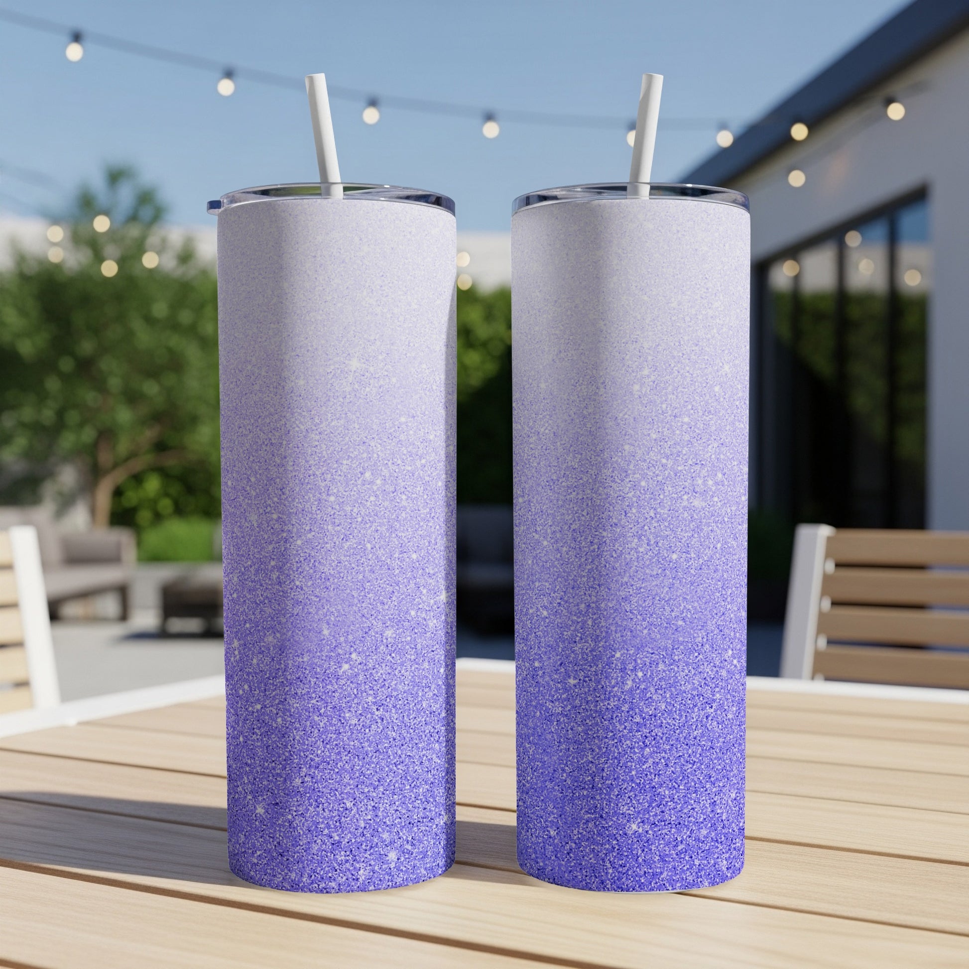 Two tall tumblers with purple glitter gradient design and straws.