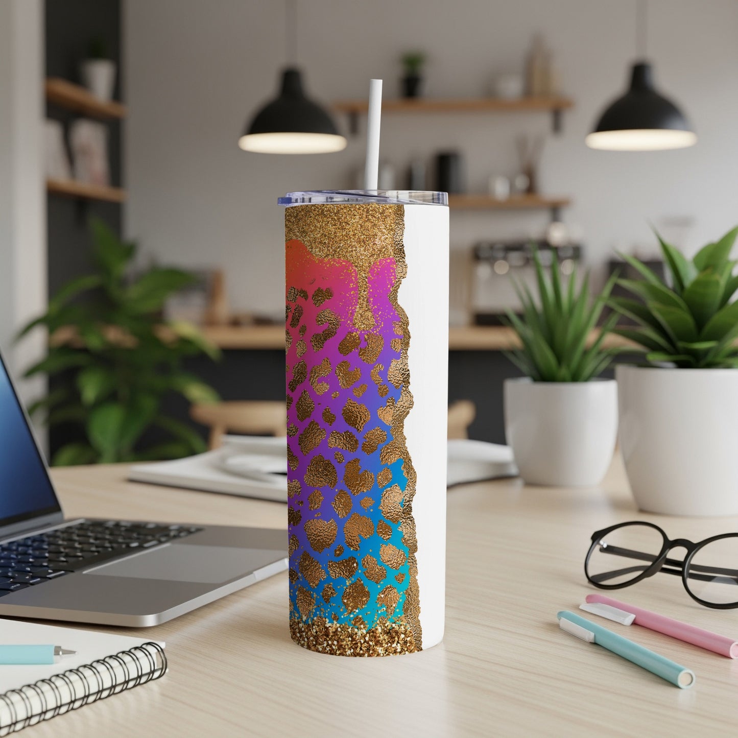 White tumbler with leopard print and glitter design, on desk with laptop and pens.