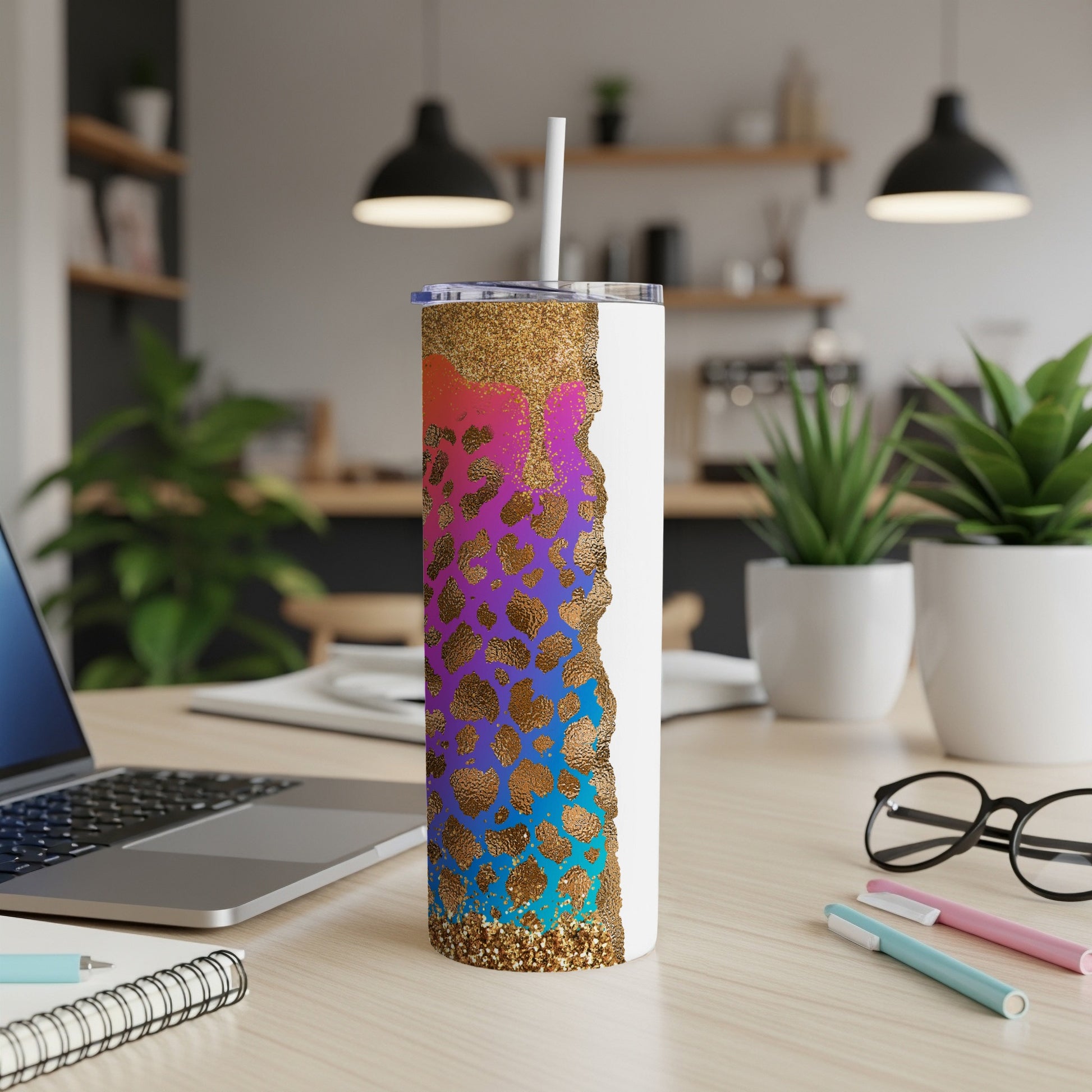 White tumbler with leopard print and glitter design, on desk with laptop and pens.