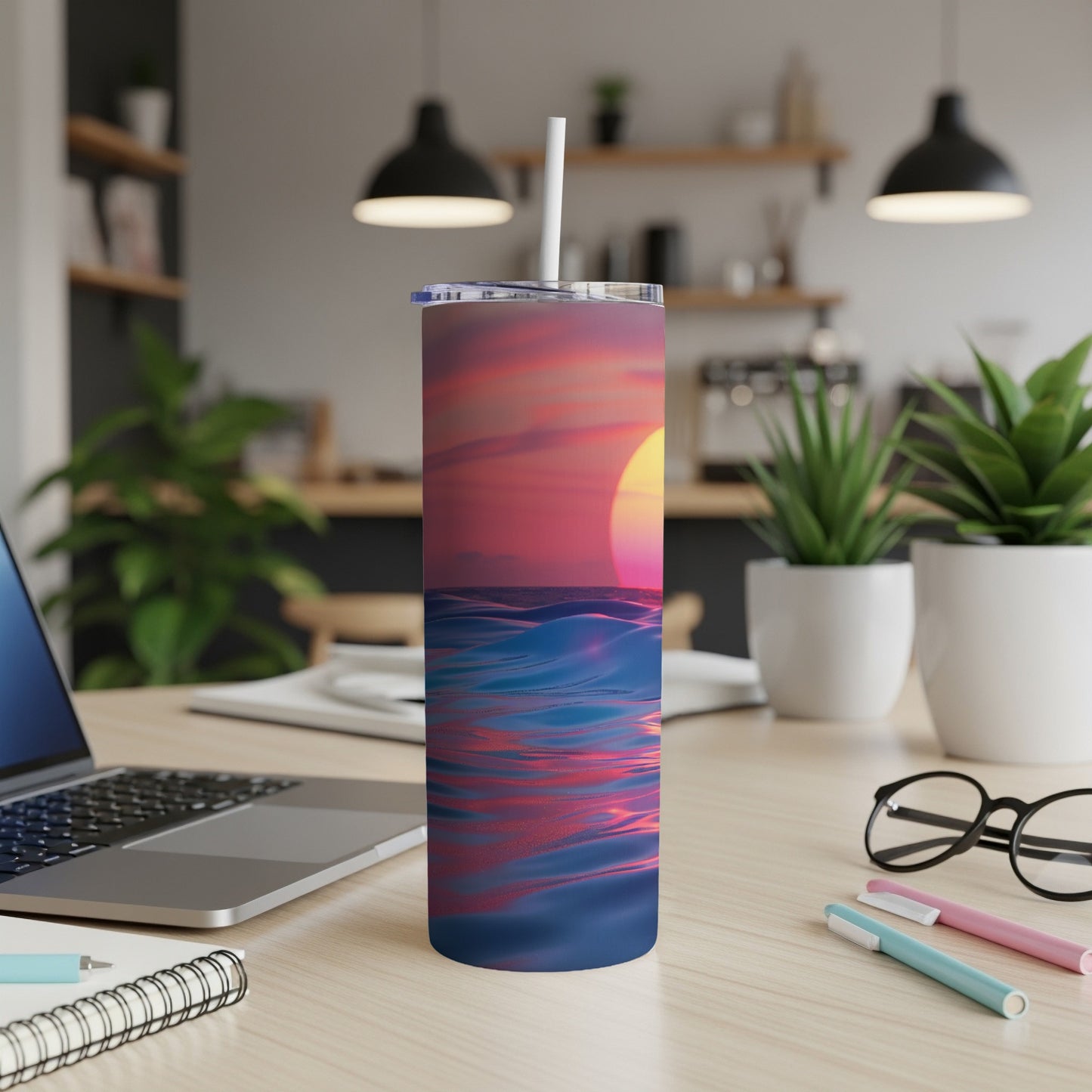 Tumbler with sunset over wavy ocean design on desk.