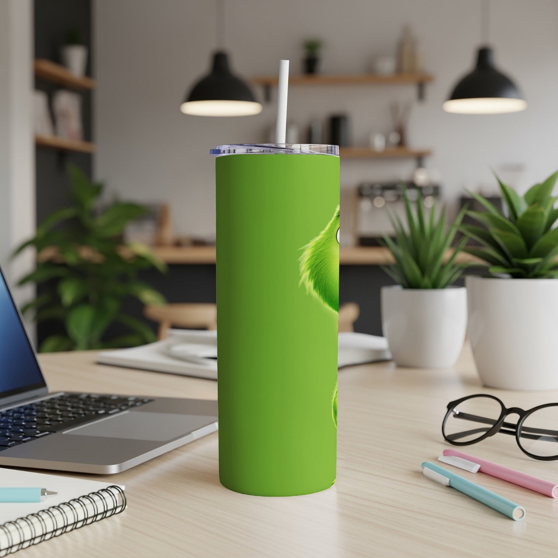 Green Grinch tumbler with a straw on a desk.