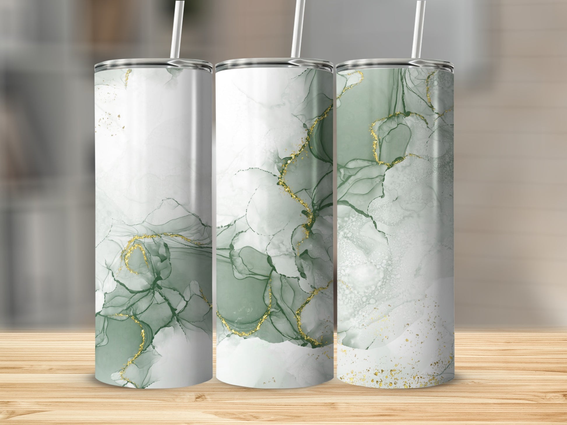 Three tumblers with green and gold marble patterns on a wooden surface.