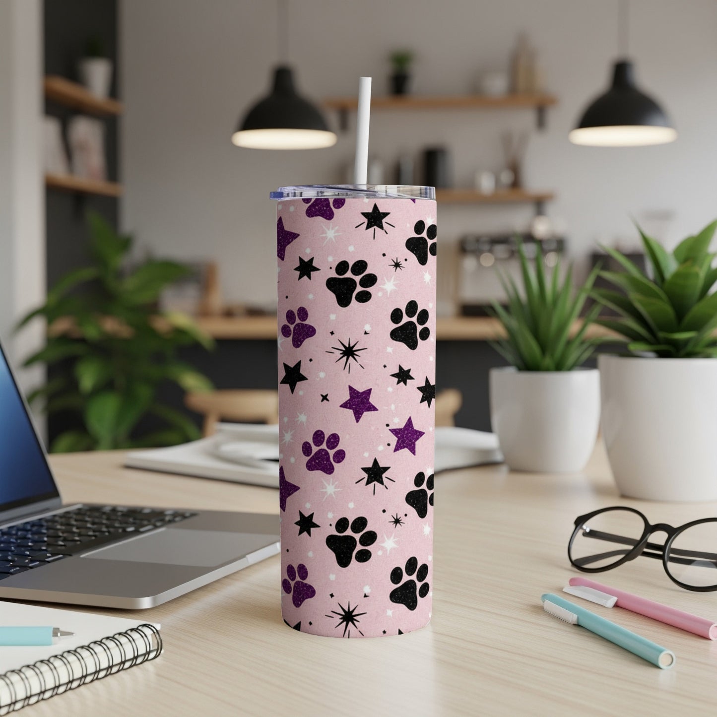 Pink tumbler with black paw prints and stars, featuring a straw.