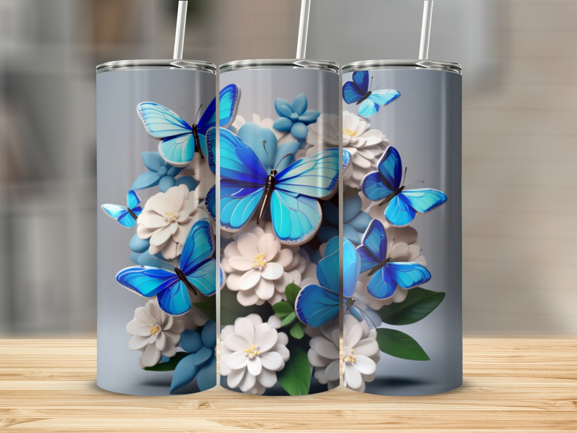 Three skinny tumblers decorated with blue butterflies and white flowers.