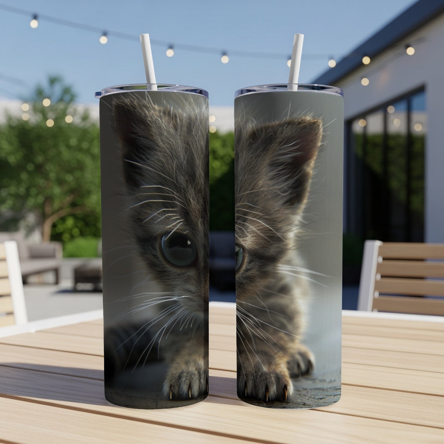 Close-up of a kitten's face on two tumblers outdoors.