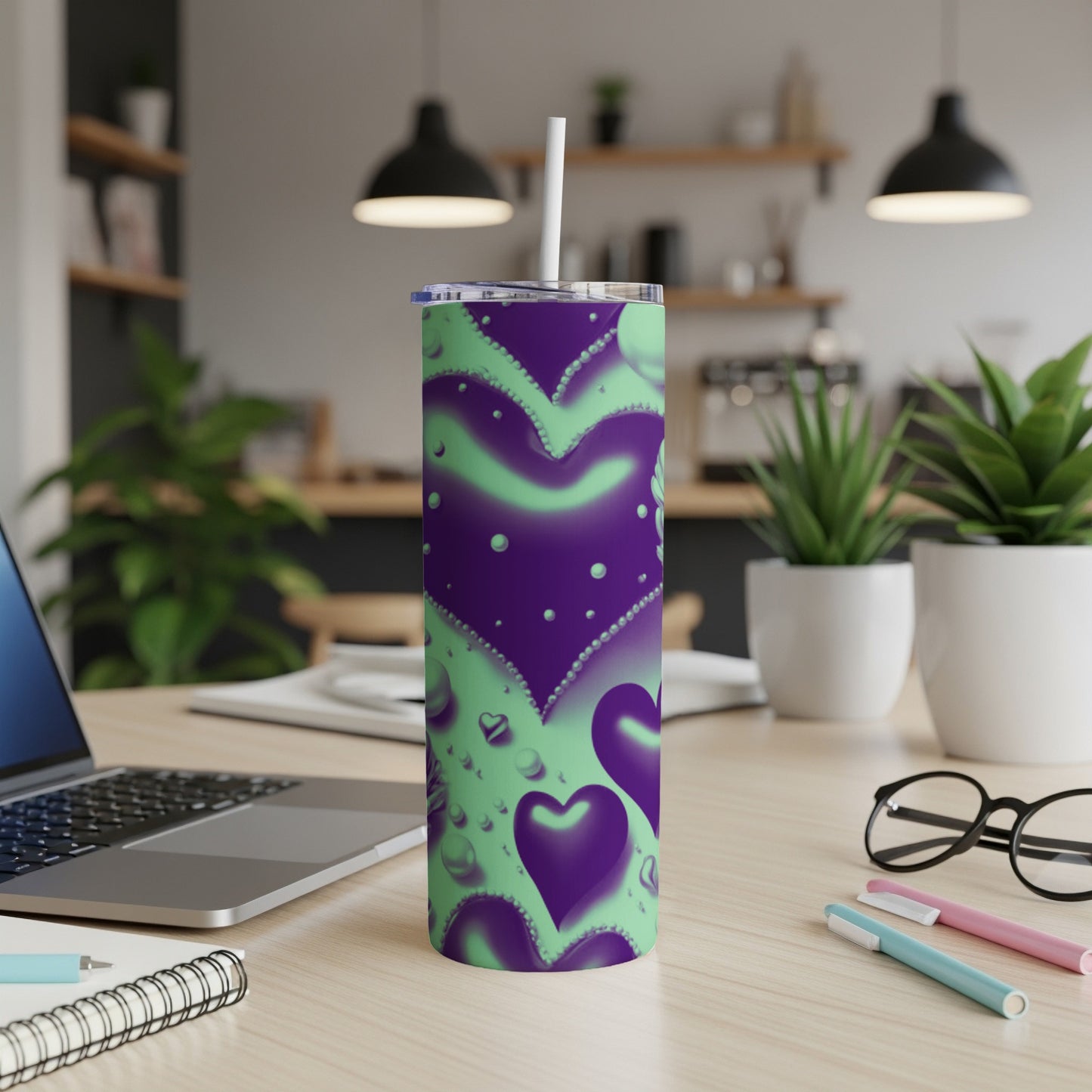 Purple and green hearts tumbler with straw on a desk.