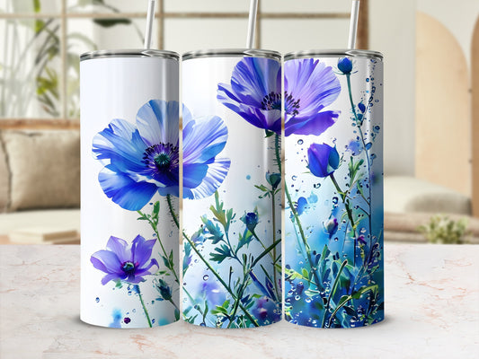 Three tumblers with vibrant blue poppy floral designs on a marble surface.