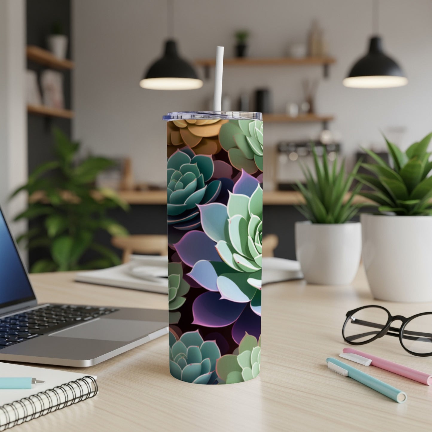 Succulent pattern on a white tumbler with a straw, on a wooden desk.