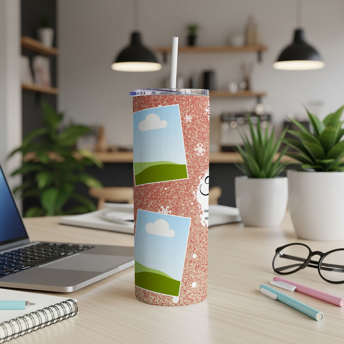 Glittery pink tumbler with photo frames and snowflakes on a desk.